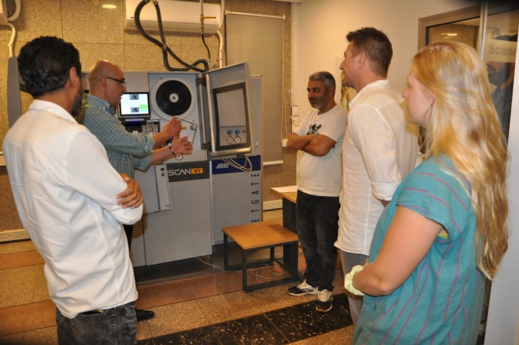 Film scanning and digital restoration in progress, with technicians applying color correction, dust/scratch removal, stabilization, and frame-by-frame enhancement to preserve audiovisual heritage.